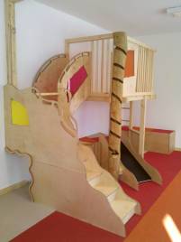 Spieletage mit organisch gesägter Treppe aus Naturholz auf rot-orangefarbenem Teppich
